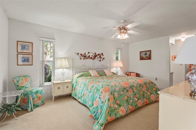 bedroom with ceiling fan, multiple windows, and light colored carpet