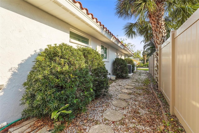 view of home's exterior with a tiled roof, fence, and stucco siding