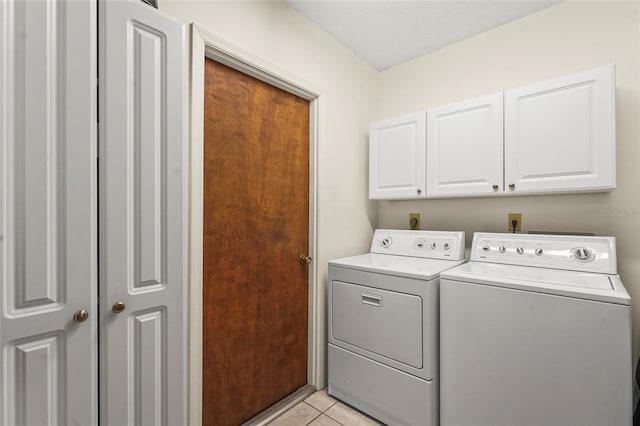 washroom featuring cabinet space, light tile patterned floors, and washer and clothes dryer