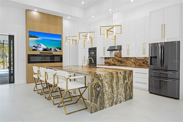 kitchen with tasteful backsplash, white cabinets, modern cabinets, under cabinet range hood, and black appliances