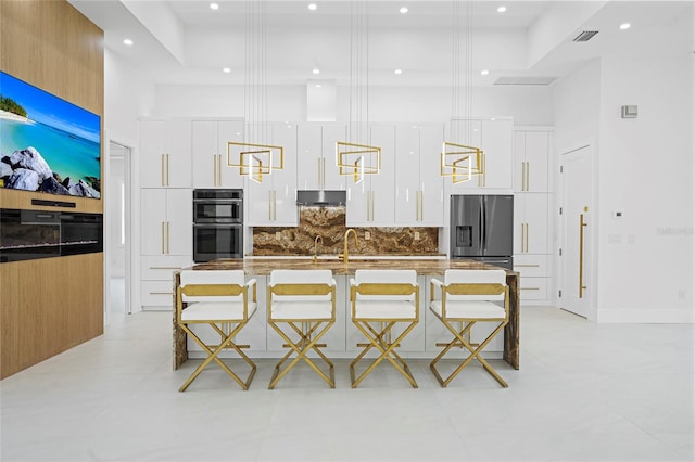 kitchen featuring under cabinet range hood, modern cabinets, a breakfast bar area, and stainless steel refrigerator with ice dispenser