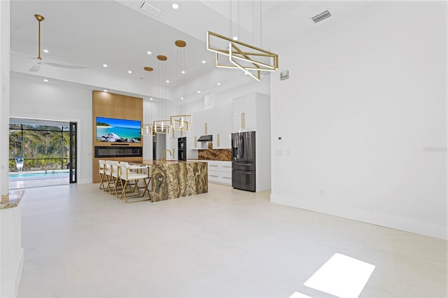 living area with a towering ceiling, baseboards, visible vents, and recessed lighting