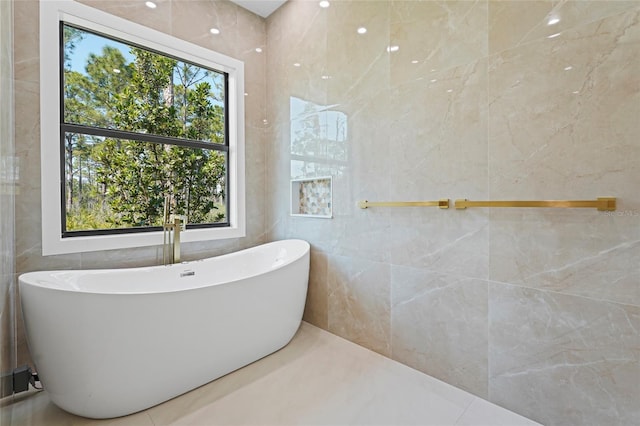 full bath featuring a soaking tub and tile walls