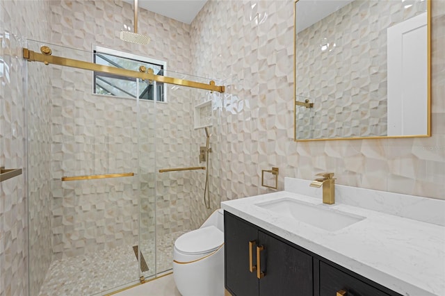 bathroom with tile walls, a shower stall, toilet, and vanity