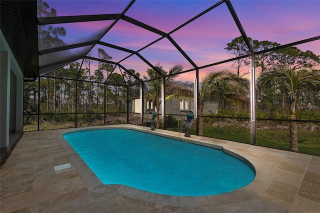 pool at dusk with glass enclosure, a patio area, and an outdoor pool