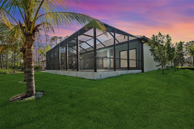 back of property with a lanai, a lawn, and stucco siding