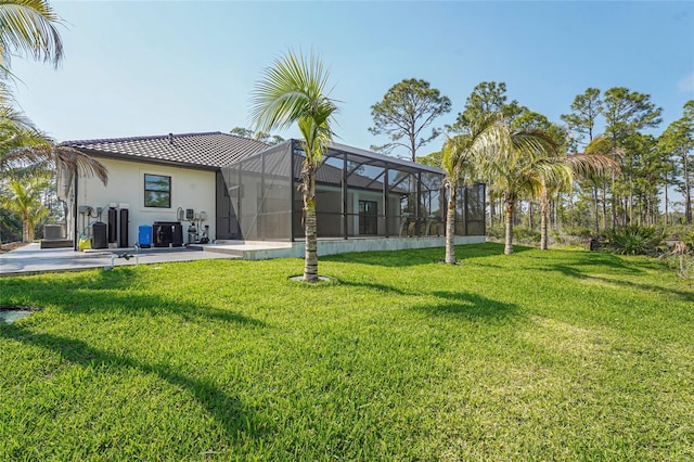 back of property with glass enclosure, a tiled roof, a yard, a patio area, and stucco siding