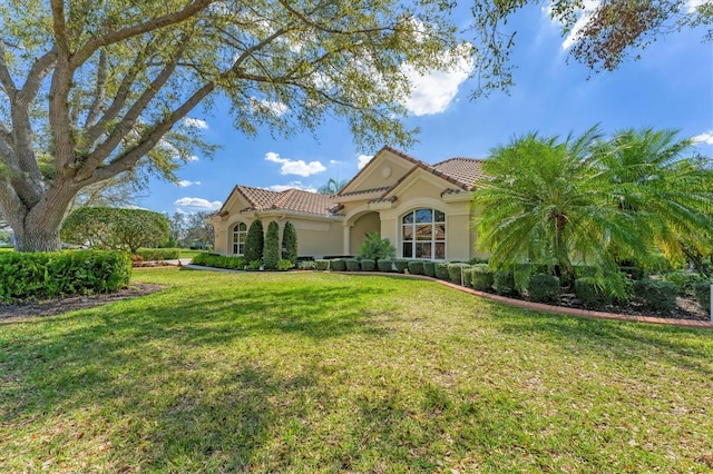 mediterranean / spanish-style home with stucco siding, a tiled roof, and a front yard