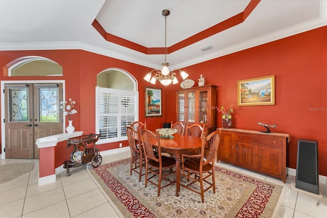 dining room with a tray ceiling, french doors, light tile patterned floors, an inviting chandelier, and ornamental molding