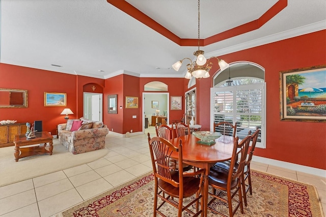 dining area with light tile patterned floors, a notable chandelier, ornamental molding, and a tray ceiling