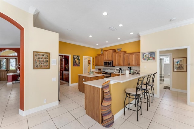 kitchen with a breakfast bar area, stainless steel appliances, a peninsula, french doors, and brown cabinets