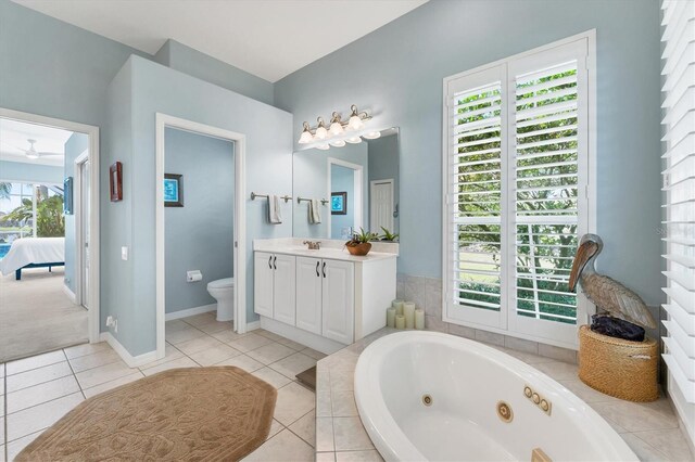 bathroom with toilet, connected bathroom, vanity, tile patterned flooring, and a whirlpool tub