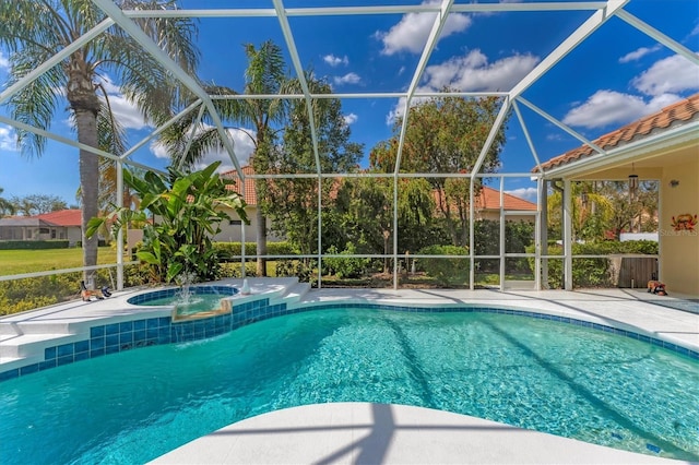 outdoor pool featuring glass enclosure, a patio area, and an in ground hot tub