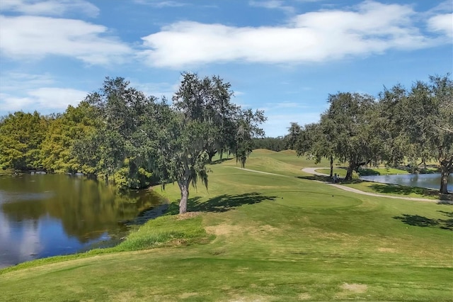 view of home's community with a water view, view of golf course, and a lawn