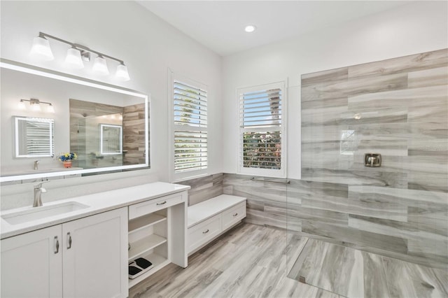 full bath with a tile shower and vanity