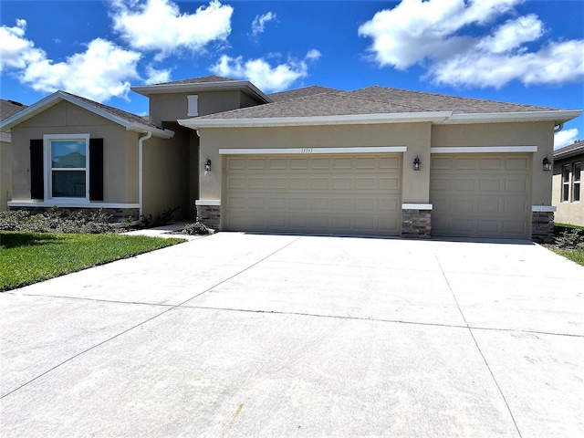 prairie-style house with stone siding, concrete driveway, an attached garage, and stucco siding