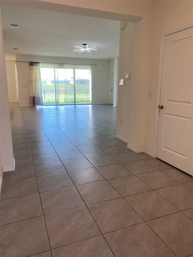 tiled empty room with baseboards, visible vents, and a ceiling fan
