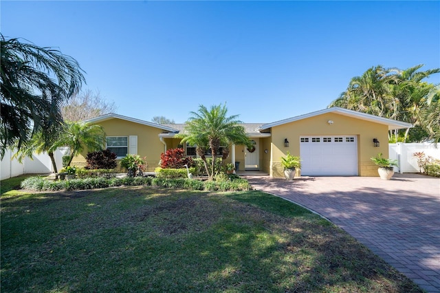 ranch-style home with decorative driveway, an attached garage, fence, and stucco siding