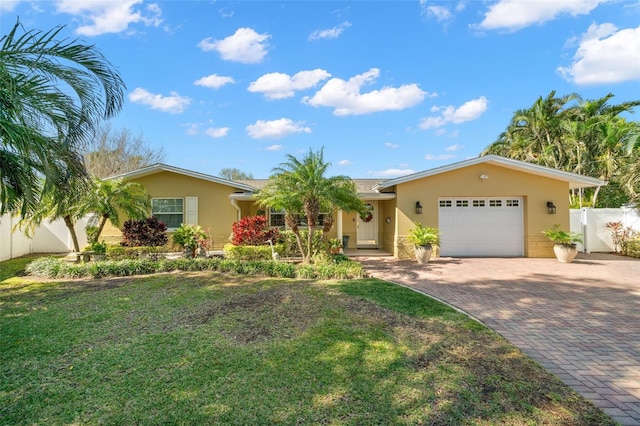 ranch-style house featuring a garage, fence, decorative driveway, stucco siding, and a front yard