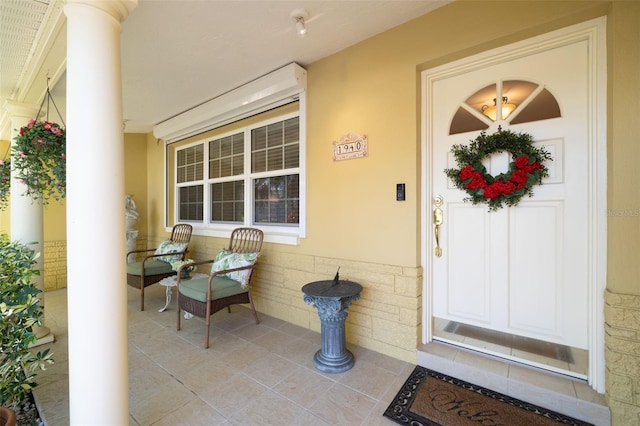 entrance to property featuring covered porch and stucco siding