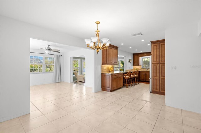 kitchen featuring recessed lighting, brown cabinets, a notable chandelier, and light tile patterned floors