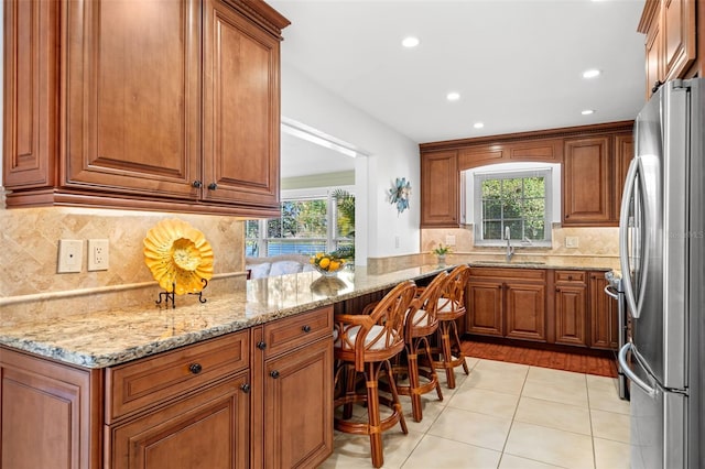 kitchen with freestanding refrigerator, brown cabinets, and a sink