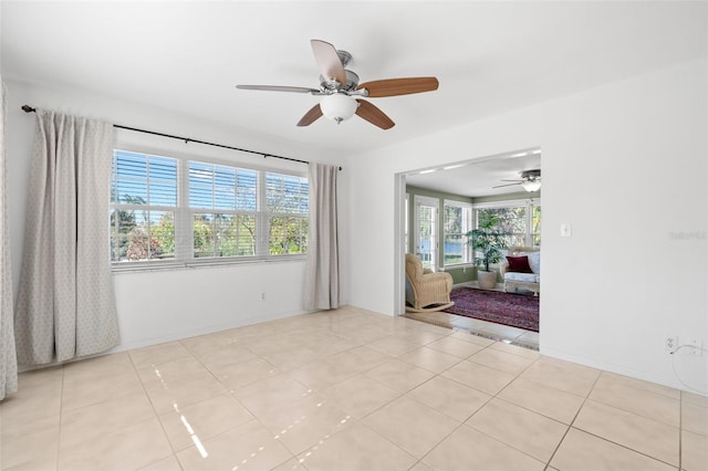 unfurnished room featuring light tile patterned floors, ceiling fan, and baseboards