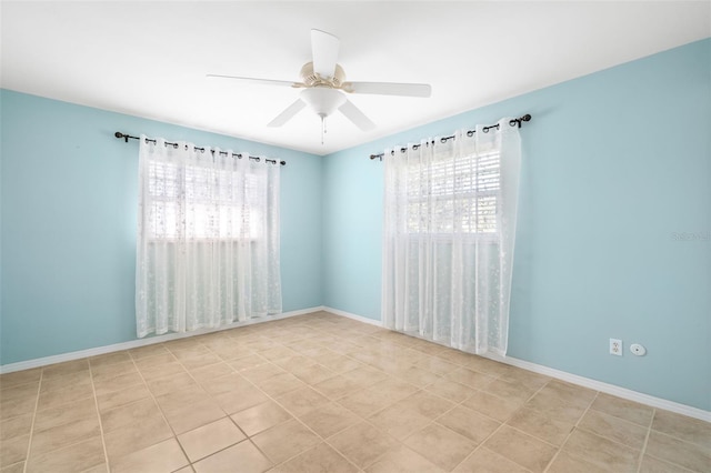 unfurnished room featuring a ceiling fan, a wealth of natural light, and baseboards