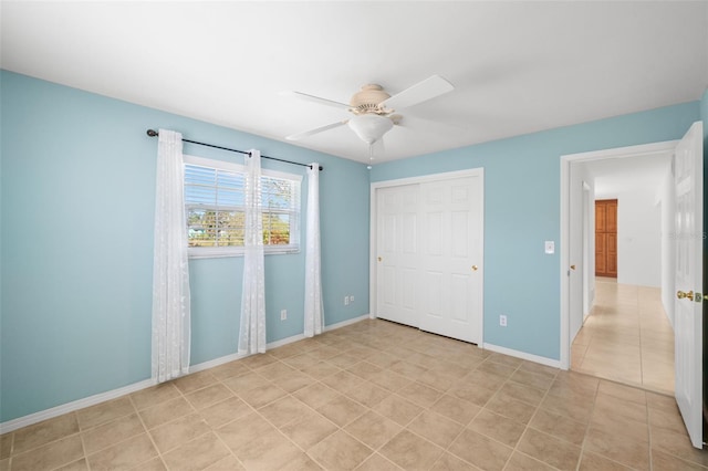 unfurnished bedroom with light tile patterned floors, ceiling fan, baseboards, and a closet