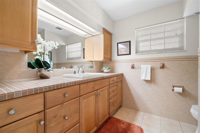 bathroom featuring tile walls, toilet, wainscoting, vanity, and tile patterned flooring