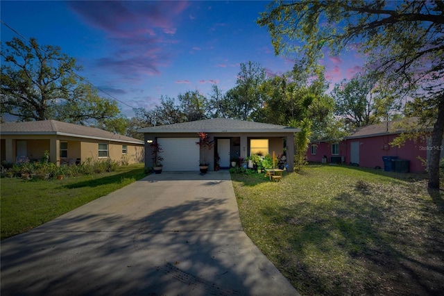 single story home with driveway, a garage, an outbuilding, a front yard, and stucco siding