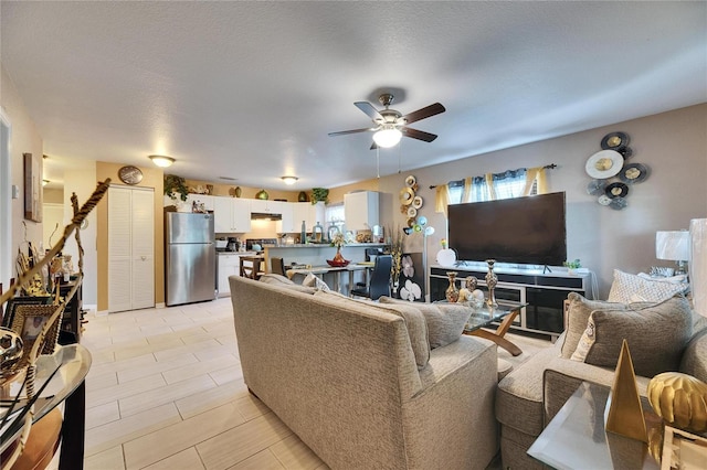 living room with a textured ceiling and a ceiling fan