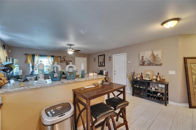 kitchen with ceiling fan, light countertops, a textured ceiling, and baseboards