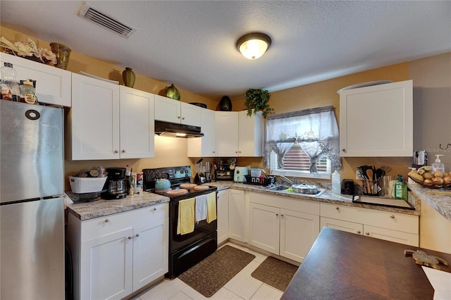 kitchen featuring under cabinet range hood, black range with electric stovetop, a sink, visible vents, and freestanding refrigerator