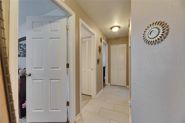 corridor with light tile patterned flooring and baseboards