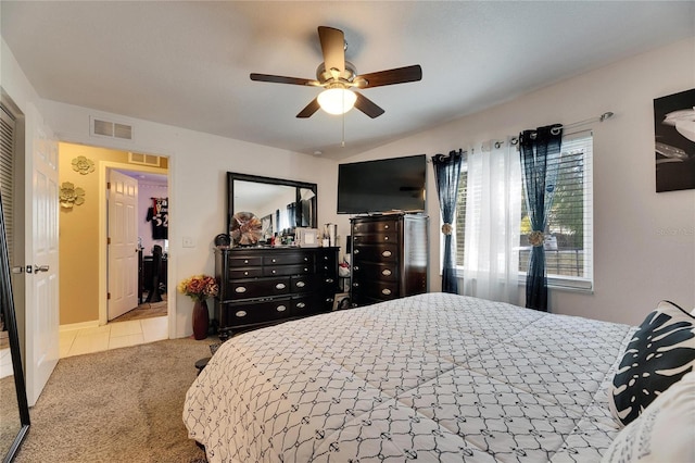 carpeted bedroom with lofted ceiling, tile patterned flooring, visible vents, and a ceiling fan