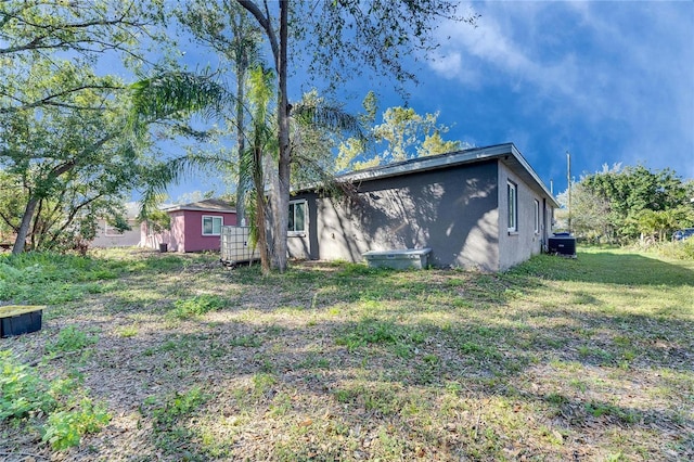 back of house with a yard and stucco siding