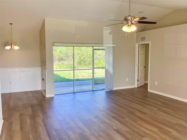 unfurnished living room with a wainscoted wall, ceiling fan with notable chandelier, wood finished floors, and visible vents