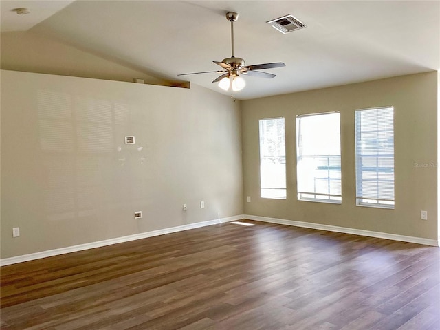 spare room with dark wood-style floors, visible vents, a ceiling fan, vaulted ceiling, and baseboards