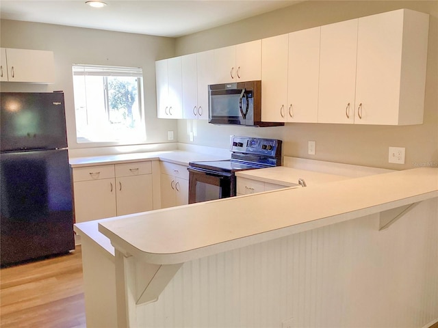 kitchen featuring light countertops, electric range, light wood-style floors, freestanding refrigerator, and a peninsula