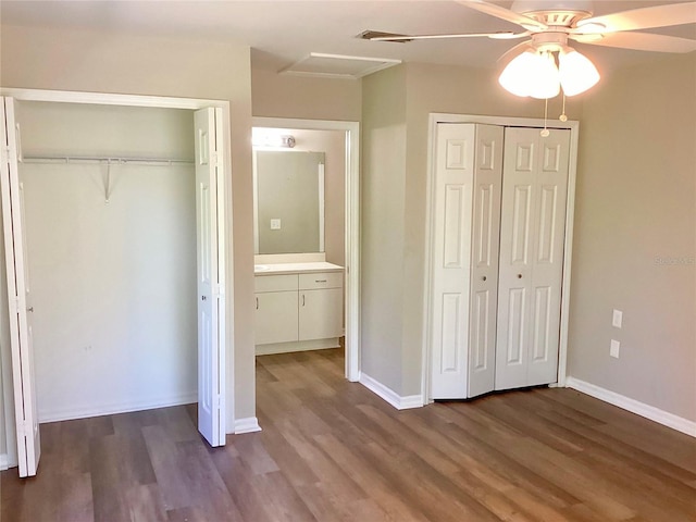 unfurnished bedroom featuring dark wood-type flooring, attic access, and baseboards