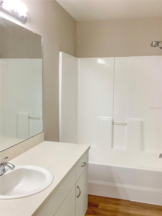 full bath with shower / bath combination, vanity, and wood finished floors