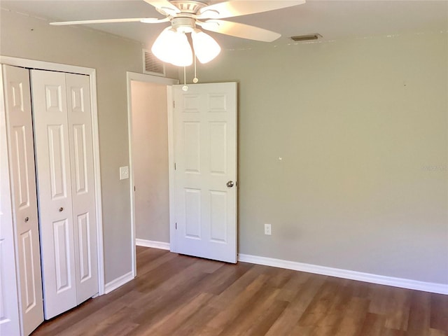 unfurnished bedroom with visible vents, a closet, baseboards, and dark wood-type flooring