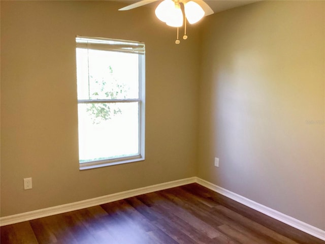 spare room featuring dark wood-style flooring, ceiling fan, and baseboards