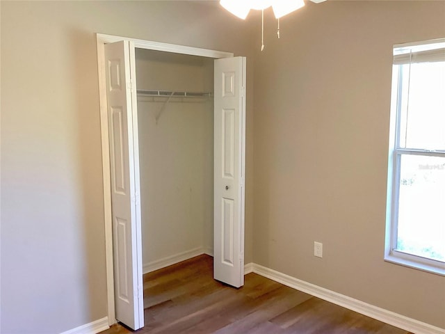 unfurnished bedroom with a closet, baseboards, and wood finished floors