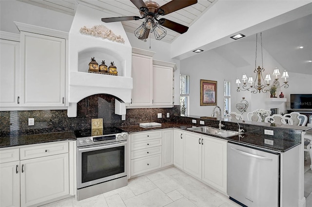 kitchen featuring lofted ceiling, appliances with stainless steel finishes, a peninsula, white cabinets, and a sink