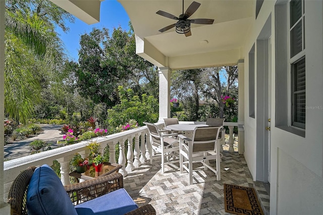 balcony with outdoor dining area, a patio, and ceiling fan