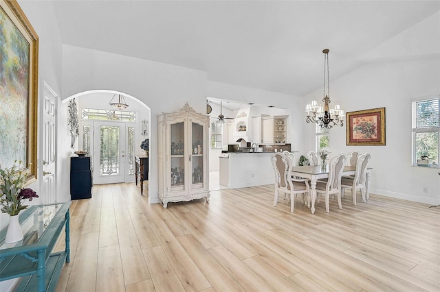 dining space featuring baseboards, vaulted ceiling, light wood-style flooring, an inviting chandelier, and arched walkways