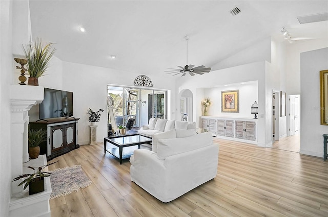 living room featuring arched walkways, visible vents, high vaulted ceiling, and light wood-type flooring