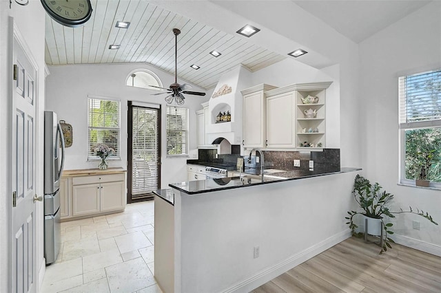 kitchen with open shelves, a sink, decorative backsplash, stainless steel refrigerator with ice dispenser, and a wealth of natural light